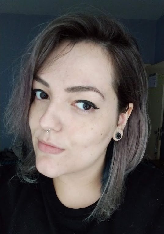 Close-up portrait of a person with short, wavy hair and earrings, looking slightly to the side.